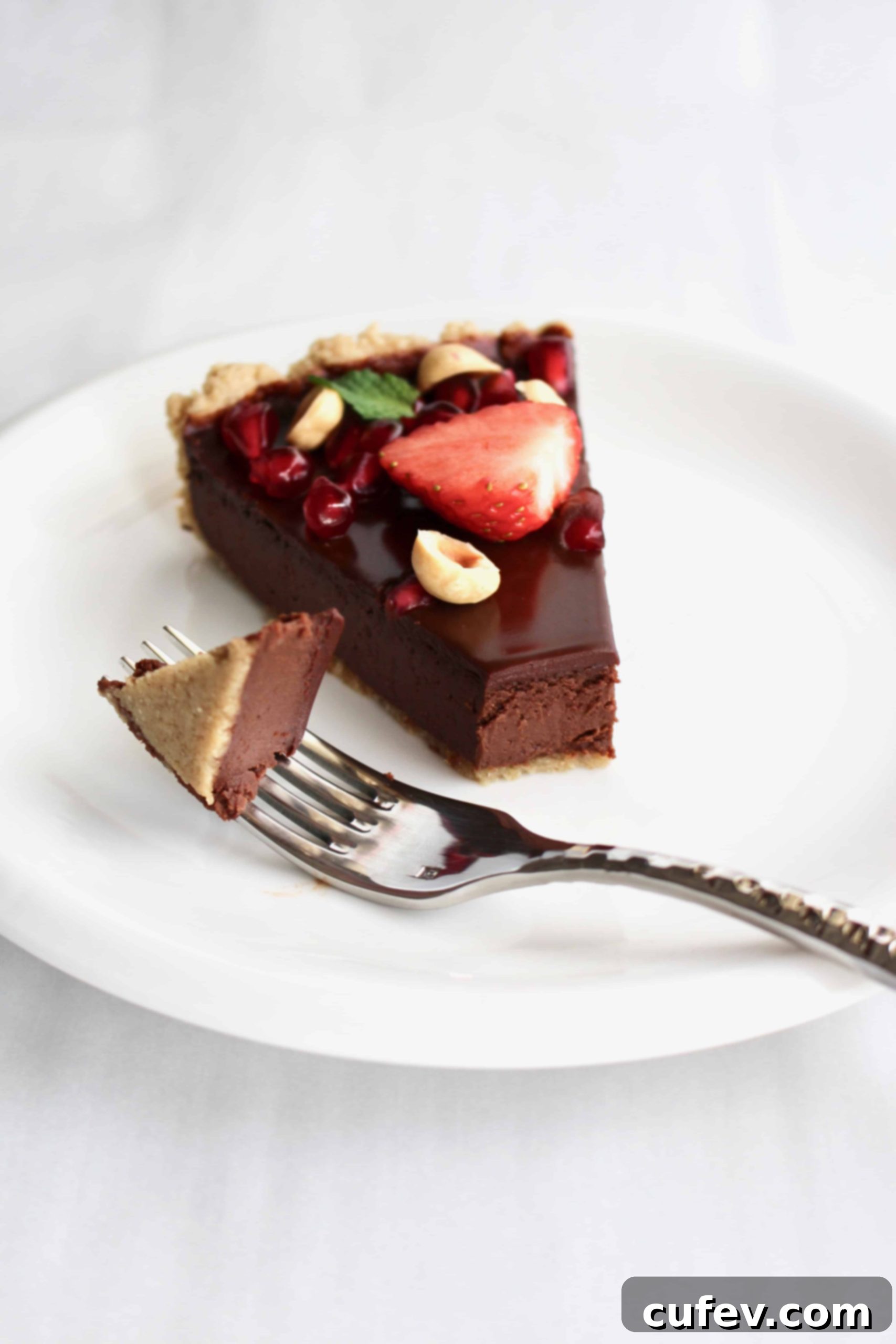 Velvet Bailey's Chocolate Delight 8 A slice of Bailey's dark chocolate tart, featuring the rich filling, oat crust, and vibrant fresh fruit and nut toppings, enticingly displayed.