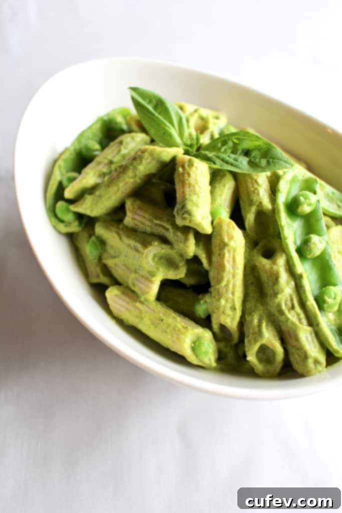 A close-up view of creamy green vegan mac and cheese in a bowl, highlighting the rich sauce and pasta texture.
