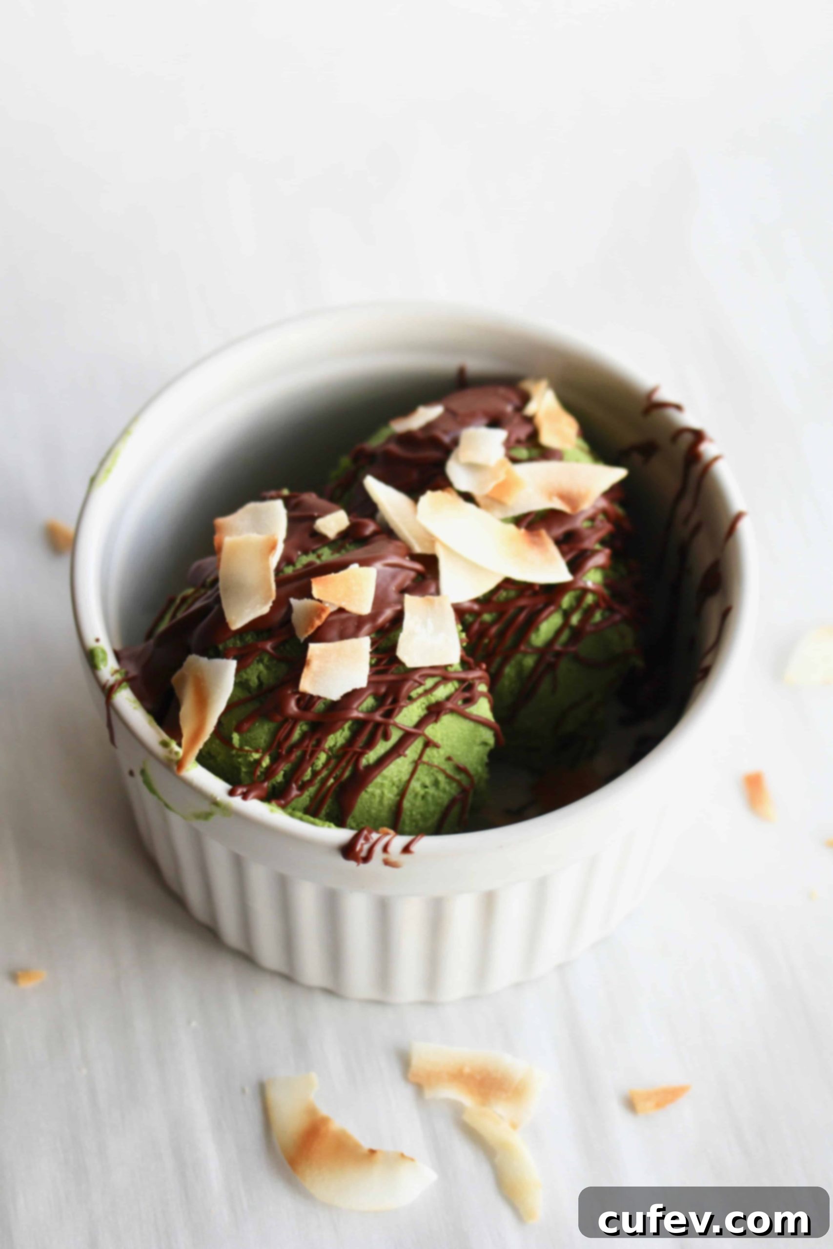 Green vegan matcha ice cream topped with a drizzle of chocolate magic shell and shredded coconut flakes.