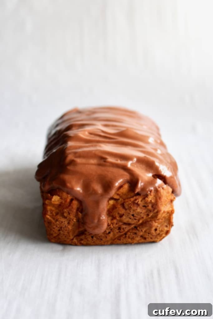 Close-up of a Brazilian carrot cake loaf, showcasing the smooth texture and thick chocolate brigadeiro frosting.