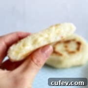 A hand holding an arepa with cheese.