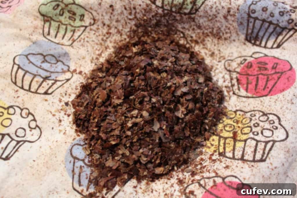 Hands vigorously rubbing roasted hazelnuts together inside a tea towel to remove their skins.