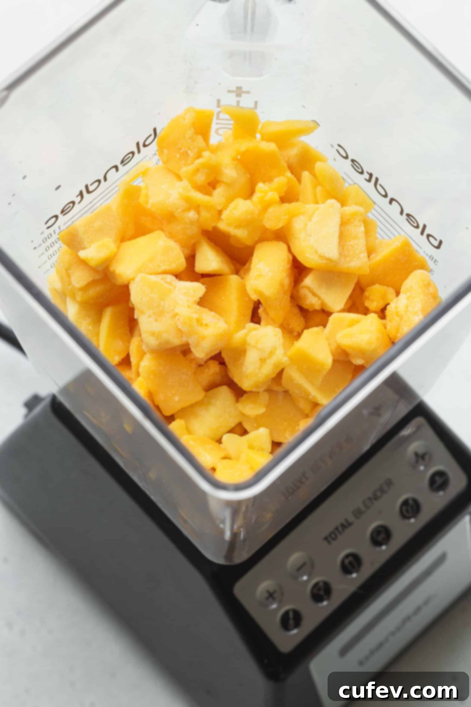 Two Ingredient Mango Sorbet 4 Close-up of frozen mango cubes being added to a food processor for blending