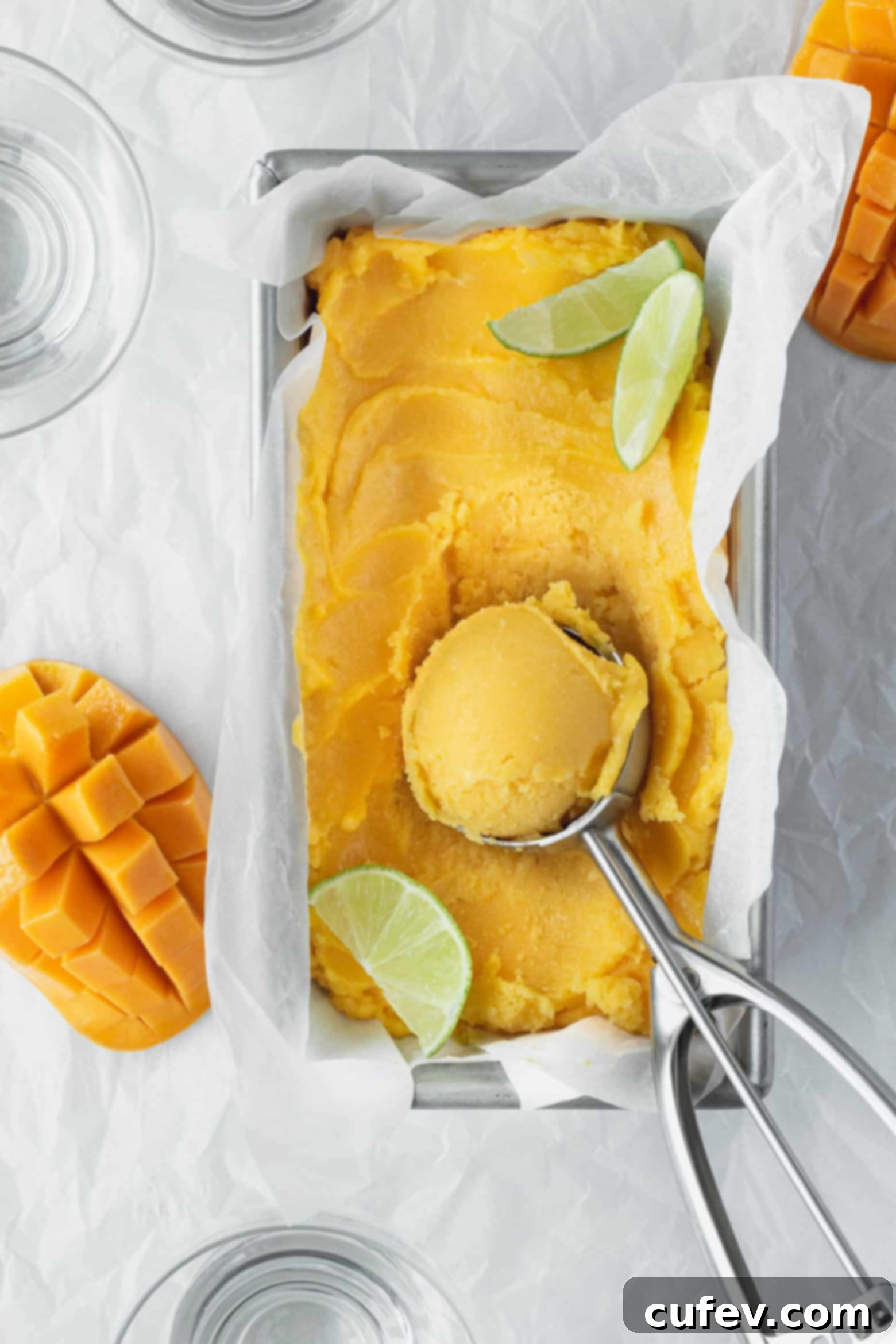 Two Ingredient Mango Sorbet 6 Homemade mango lime sorbet scooped into a pan, ready to be served with an ice cream scoop