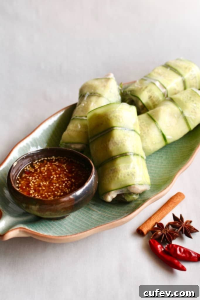 Spicy chicken summer rolls on a green dish with a small bowl of chili oil.