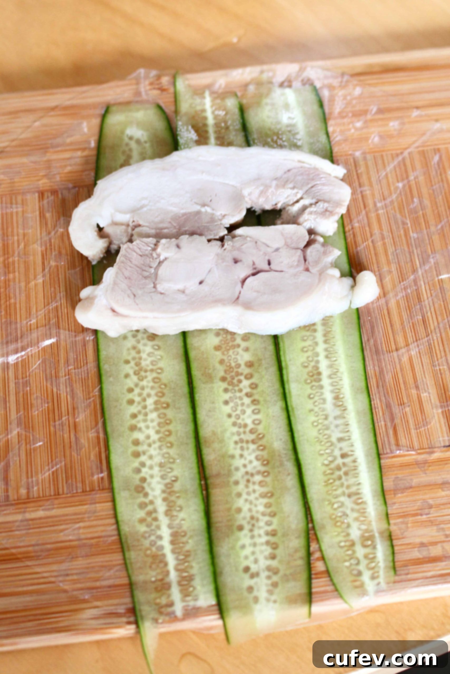 Sliced chicken thigh on sliced cucumbers.