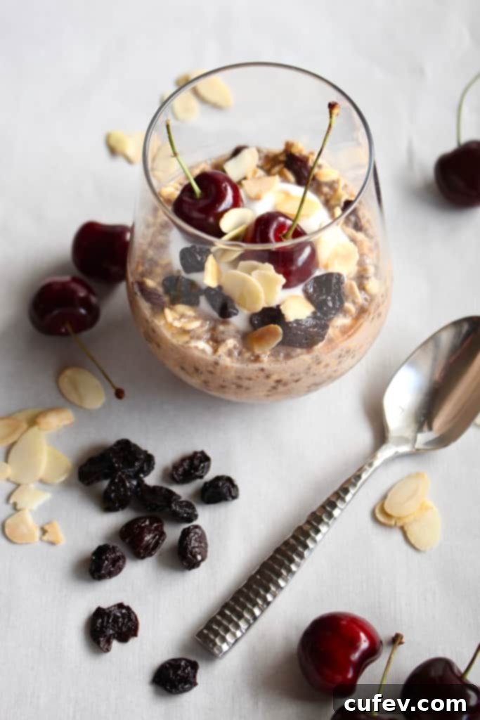 A glass of overnight oats with a silver spoon next to it.
