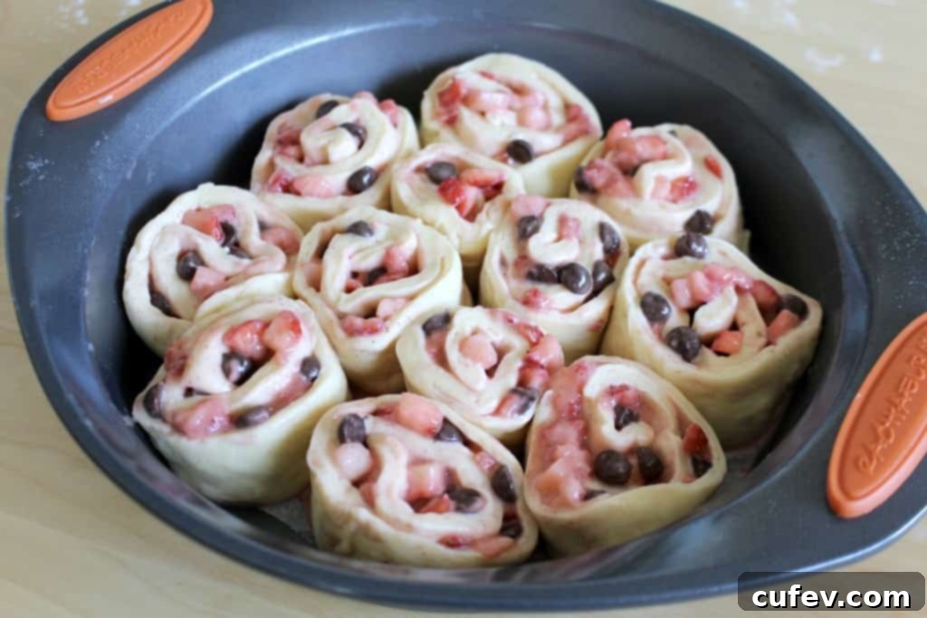 Dough log, neatly rolled and ready to be sliced, showing the swirls of strawberry and chocolate filling.