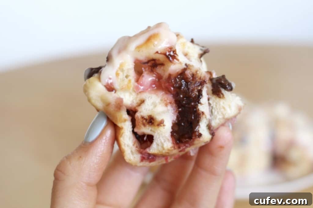 Close-up of a single strawberry chocolate roll, revealing its fluffy interior, melted chocolate, and luscious strawberry swirls.