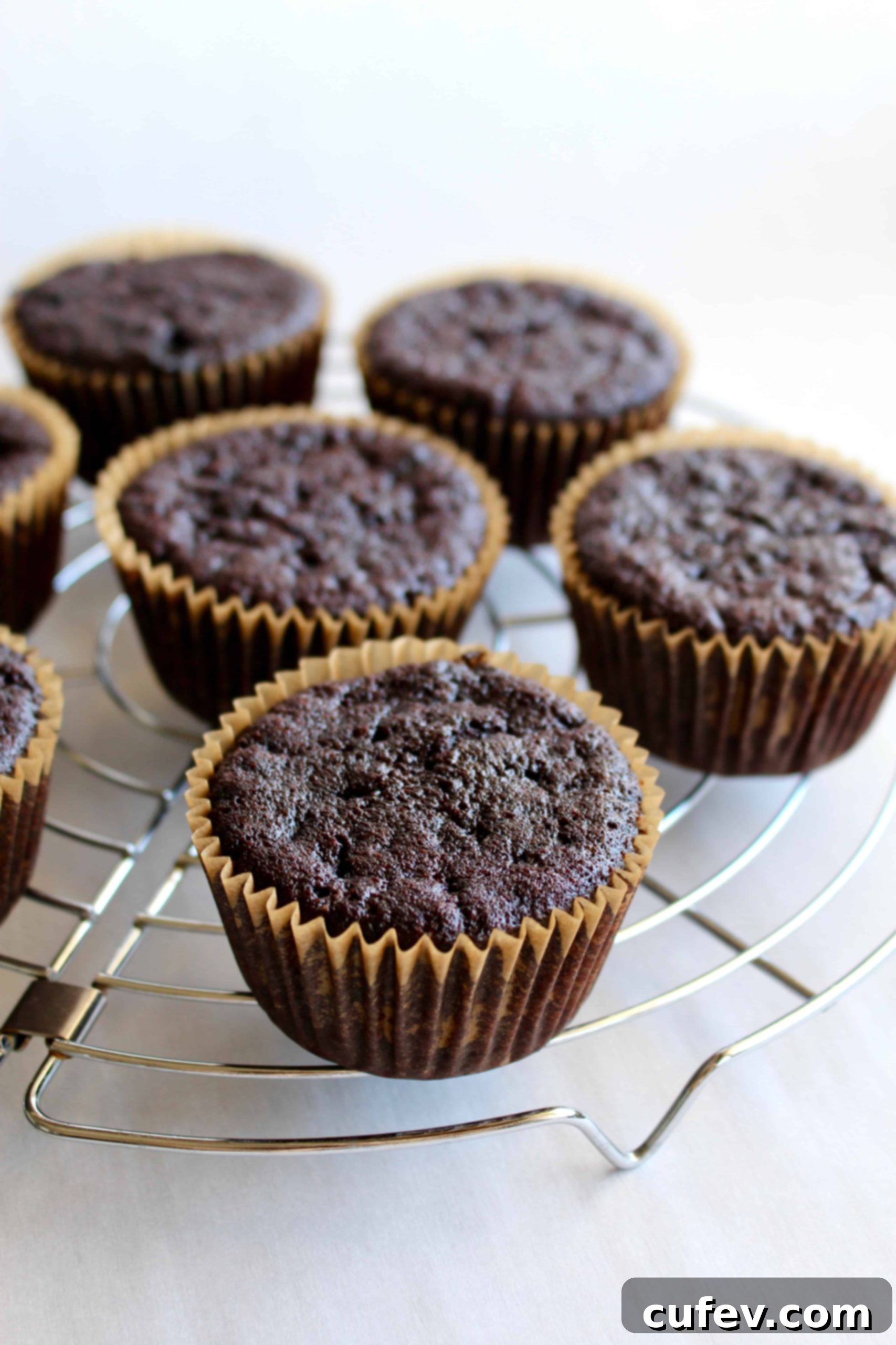 Freshly baked vegan chocolate cupcakes cooling on a wire rack, ready for filling and frosting.