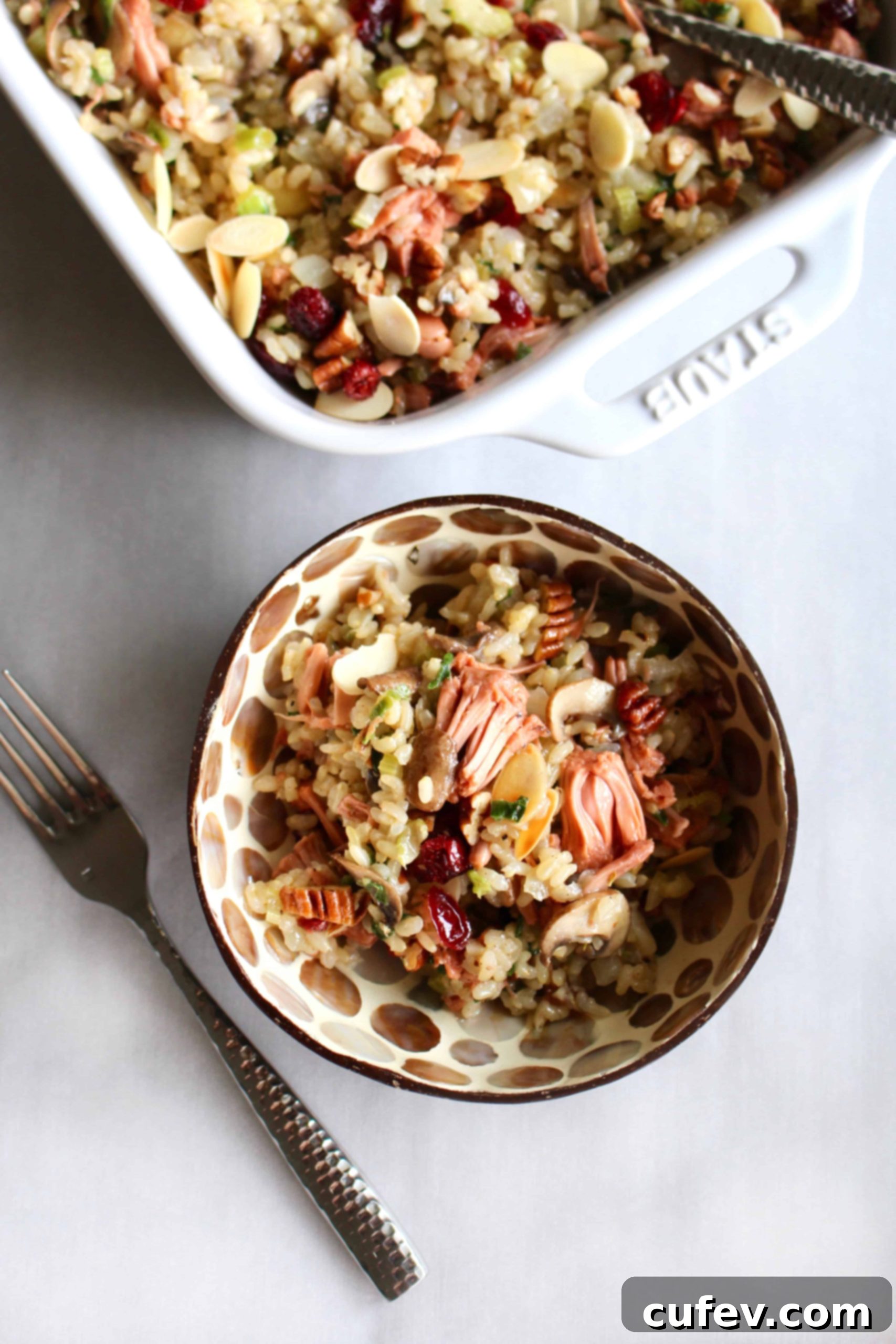 A generous serving of vegan brown rice and jackfruit stuffing in a white bowl, showcasing its rich texture and colorful ingredients.