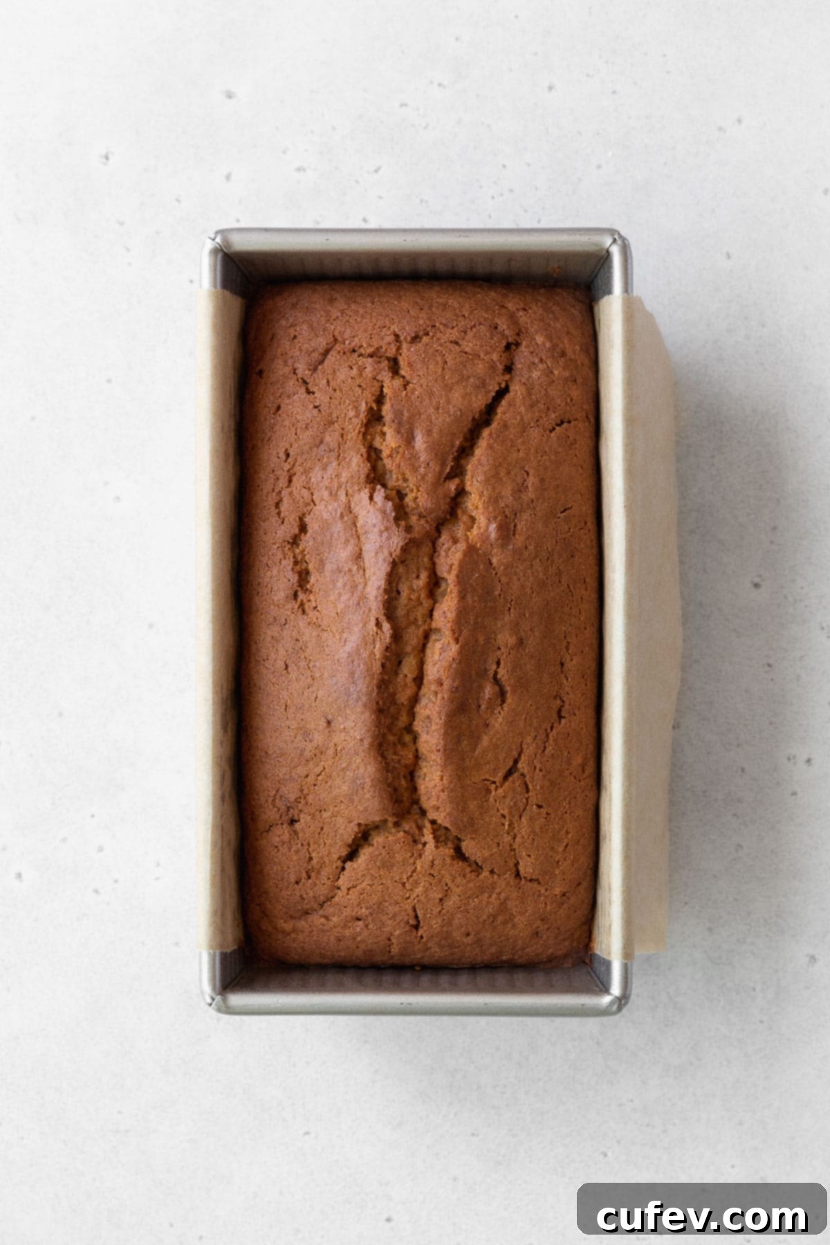 Overhead shot of a beautifully baked sweet potato loaf cake, still warm, resting in its metallic pan.