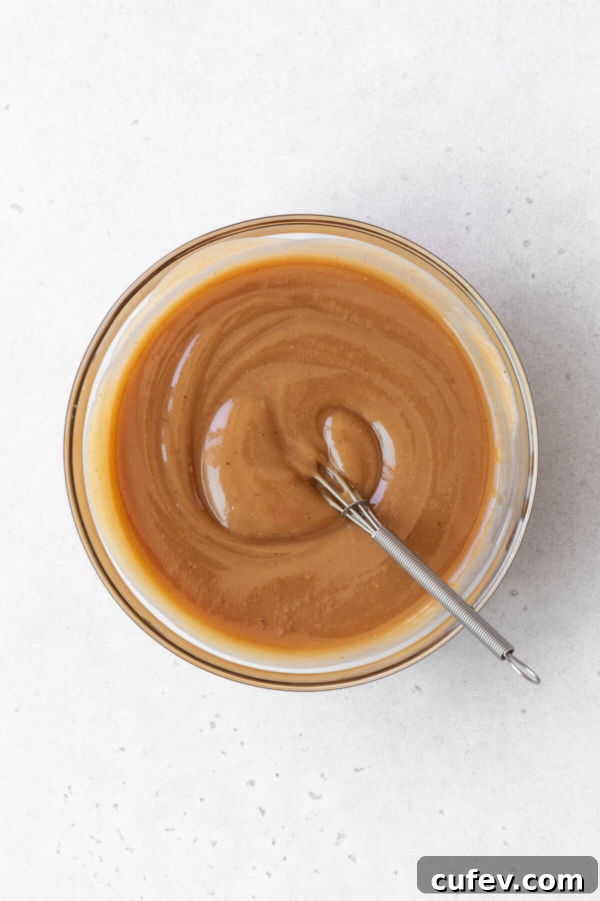 A glass bowl filled with all the maple cashew frosting ingredients, perfectly mixed into a smooth, creamy base.