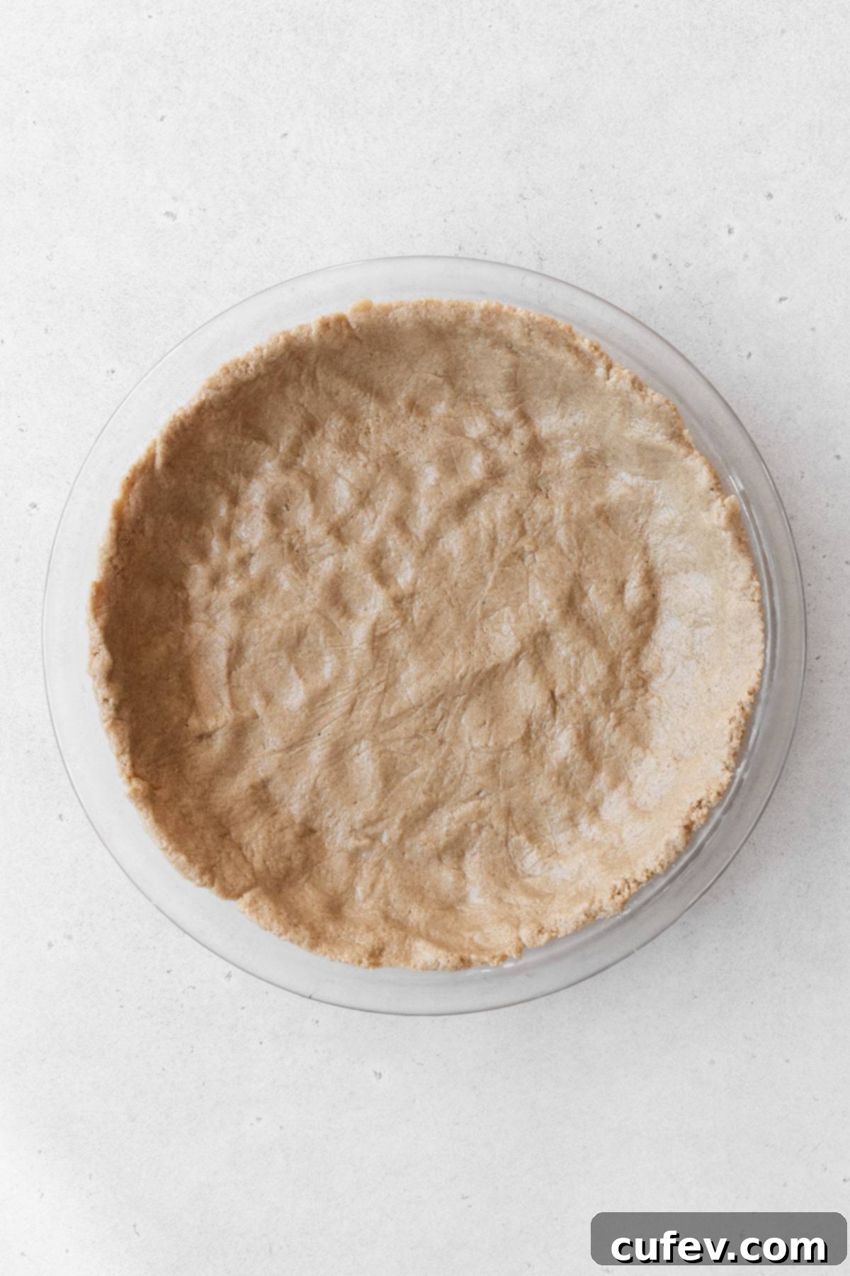 The oat crust dough beautifully pressed into a glass pie dish, forming a neat and sturdy base.