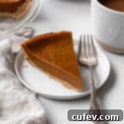 A square image depicting a delightful slice of eggless pumpkin pie on a white dessert plate, with a silver fork positioned elegantly beside it, ready to be enjoyed.