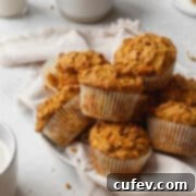 square image of a pile of healthy morning glory muffins on a white plate.