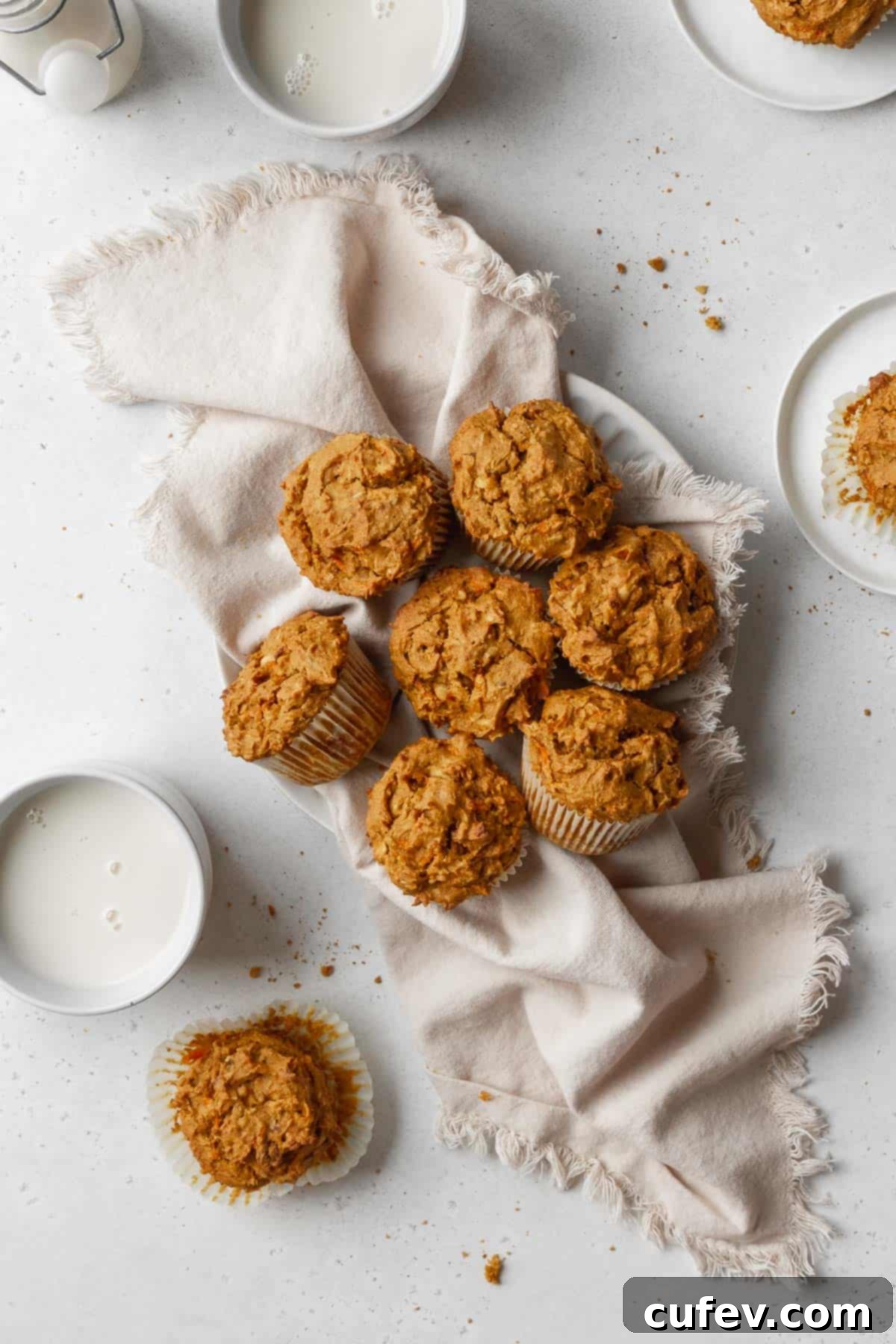 Overhead hero shot of healthy vegan morning glory muffins on a white kitchen towel on a white table.