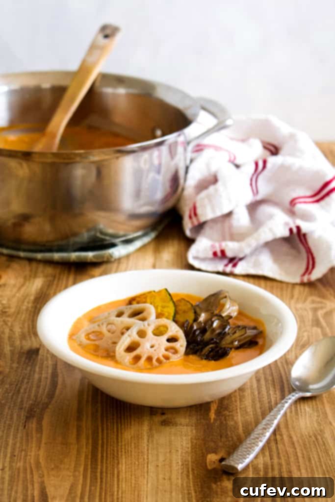 Close-up of a vibrant vegan coconut curry, rich and creamy, garnished with fresh herbs and featuring seasonal vegetables like kabocha squash, lotus root, and maitake mushrooms.