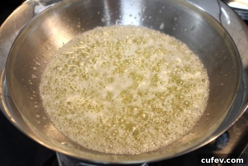Unsalted butter melting and bubbling in a small saucepan over low heat, beginning the browning process.
