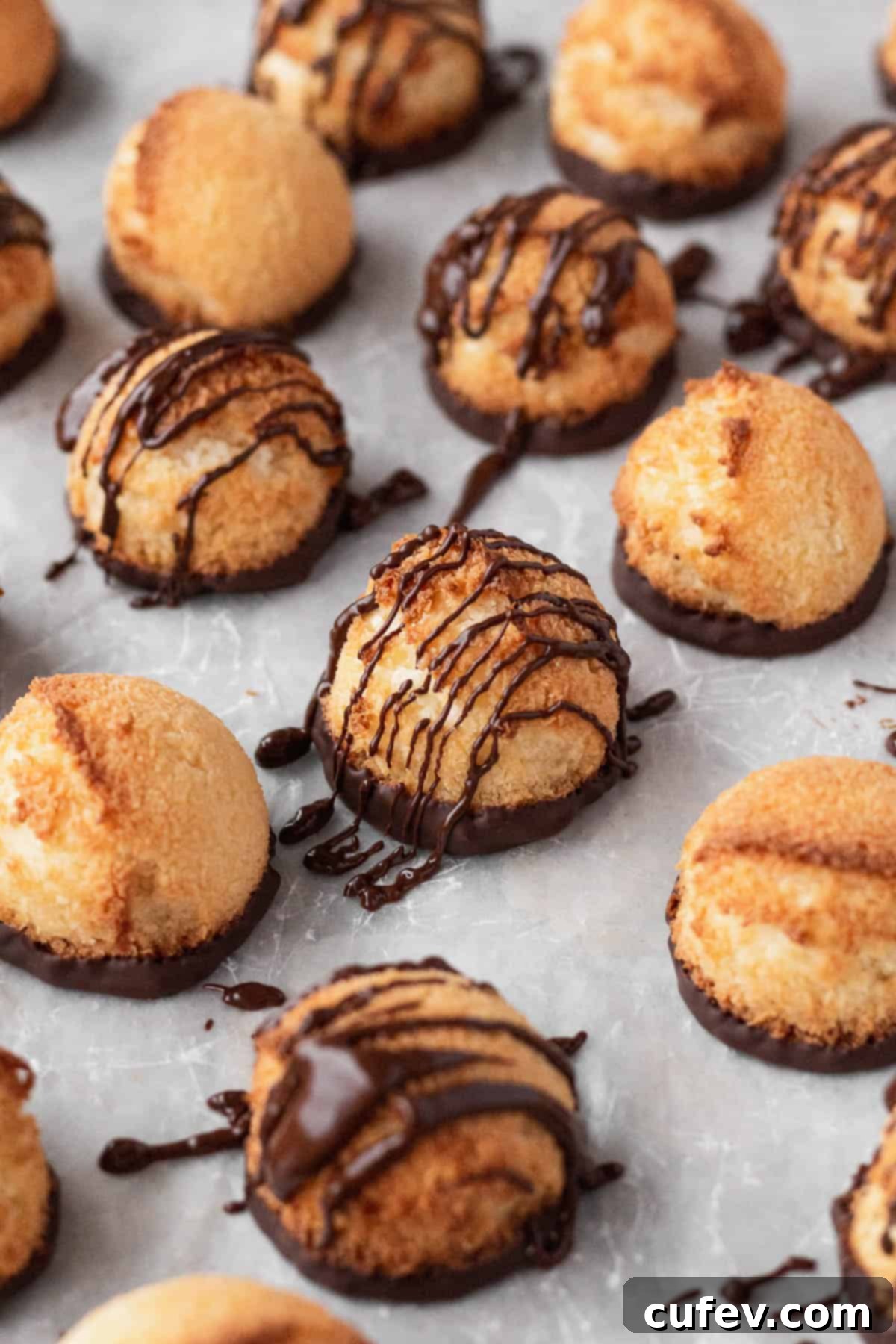 Plain and chocolate drizzled vegan coconut macaroons on a white surface, showcasing their golden texture and enticing appearance.
