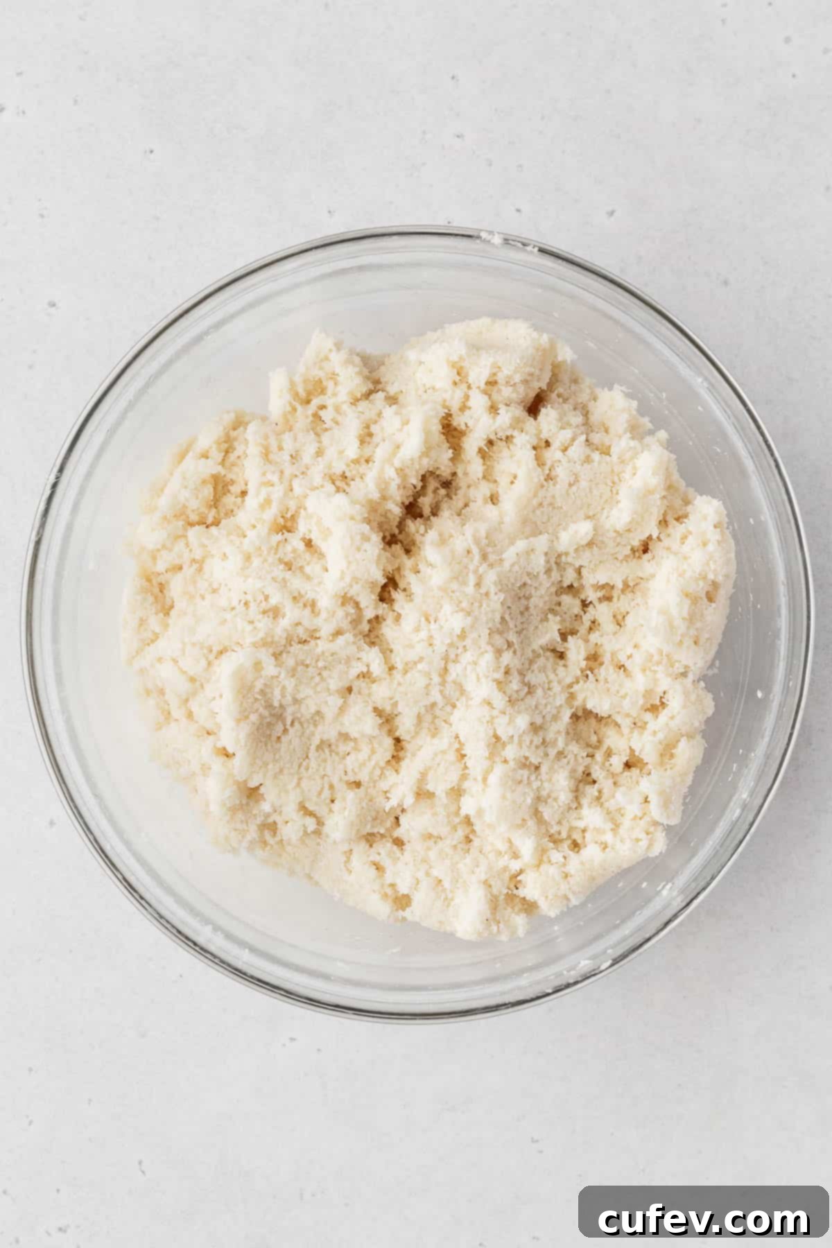 Vegan coconut macaroon dough, freshly mixed and ready for scooping, in a glass bowl.