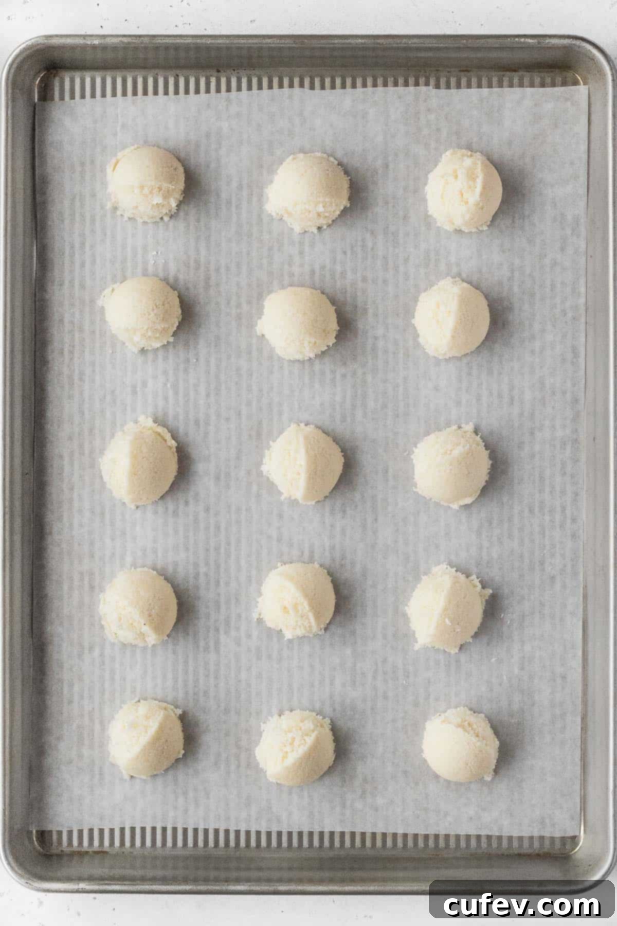 Vegan macaroon dough carefully scooped and arranged on a parchment paper-lined baking sheet.