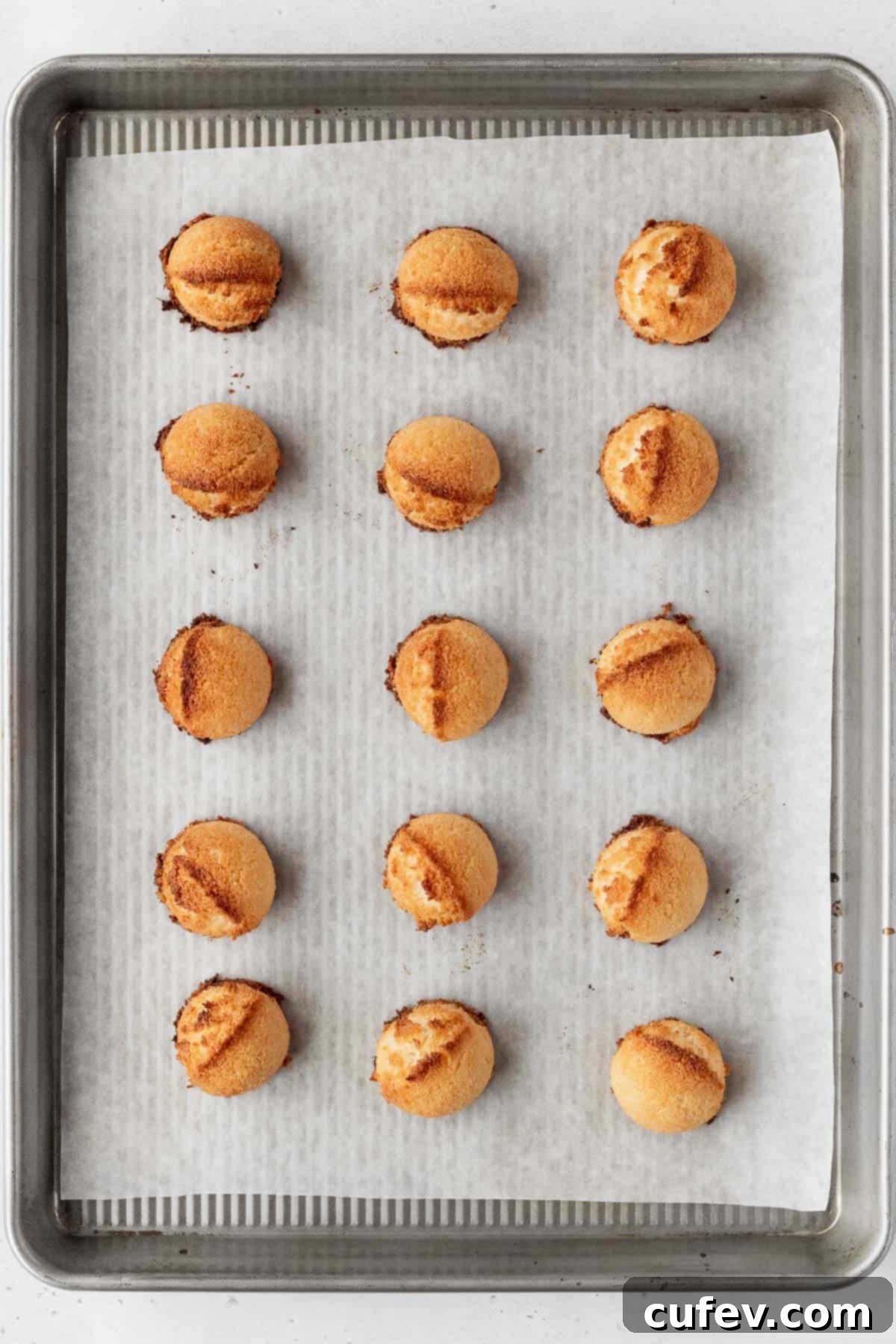 Freshly baked vegan coconut macaroons, still warm and golden on the baking sheet.
