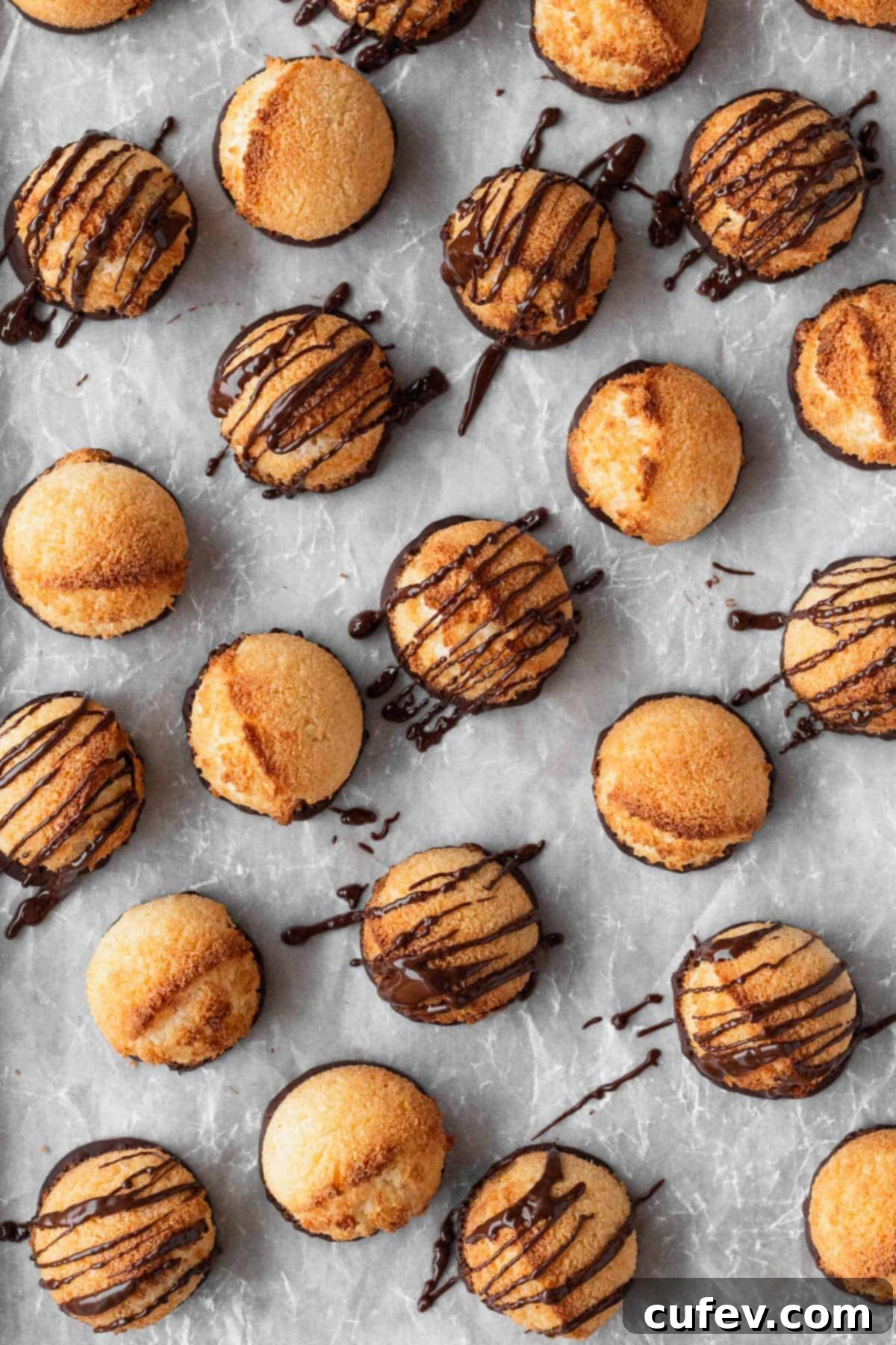 Vegan coconut macaroons artfully drizzled with melted chocolate, resting on parchment paper.