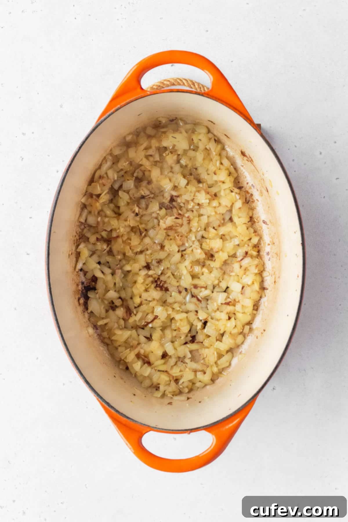 Minced onion and garlic cooking in a large enameled pot.
