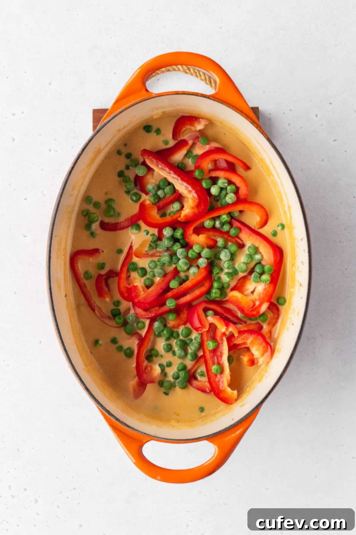 Frozen peas and sliced red bell peppers added to the pot.