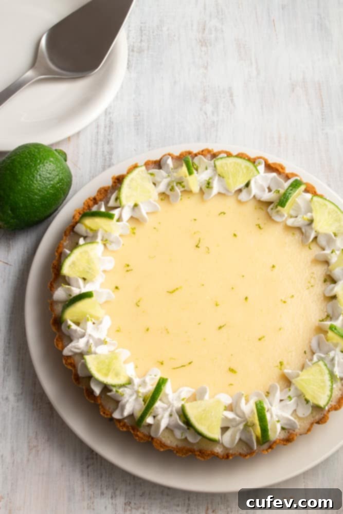 Effortless Vegan Key Lime Bliss 2 A vibrant, creamy vegan key lime pie with a golden graham cracker crust and a generous dollop of coconut whipped cream, garnished with fresh lime zest and slices.