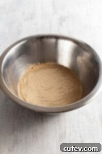 Activating dry yeast in a bowl of warm water with a spoon.