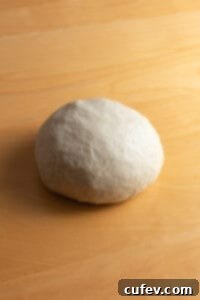 A perfectly kneaded ball of bread dough resting in a bowl.