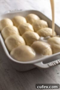 Sweet coconut sauce being poured over unbaked dough balls in a baking dish.