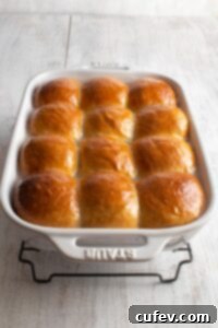 Glazed dinner rolls, freshly baked and glistening with coconut sauce in a white baking dish.