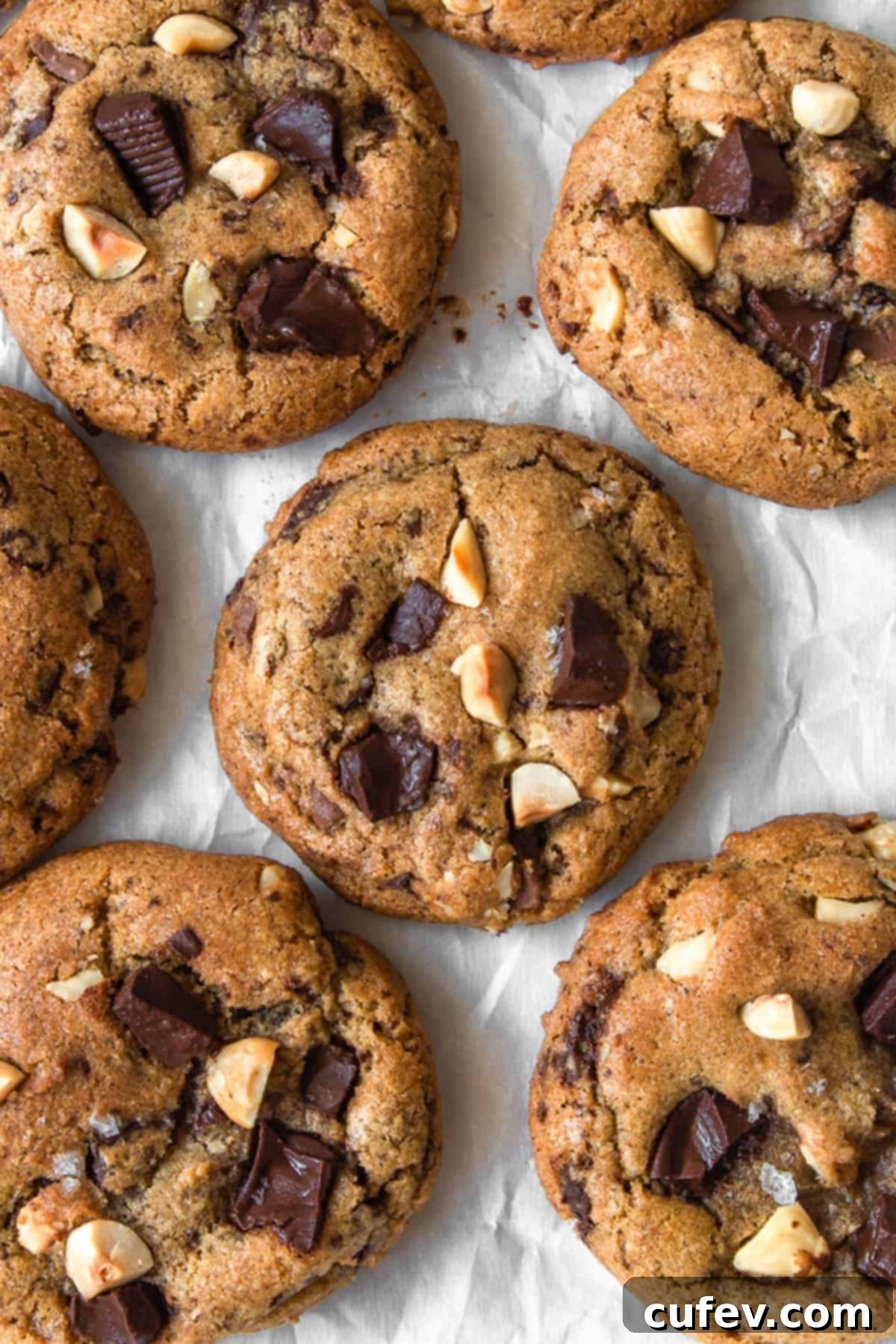 An overhead shot showcasing beautifully browned butter chocolate chip cookies arranged on parchment paper, highlighting their golden hue and molten chocolate.