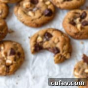 A bitten brown butter chocolate chip cookie surrounded by more cookies, showcasing the warm, inviting texture and melted chocolate.