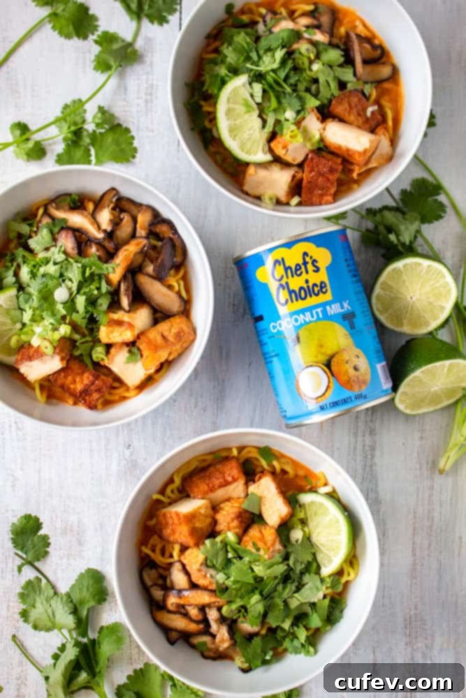 Close-up of a vibrant bowl of vegan Thai red curry ramen with deep-fried tofu, sautéed shiitake mushrooms, and fresh herbs.