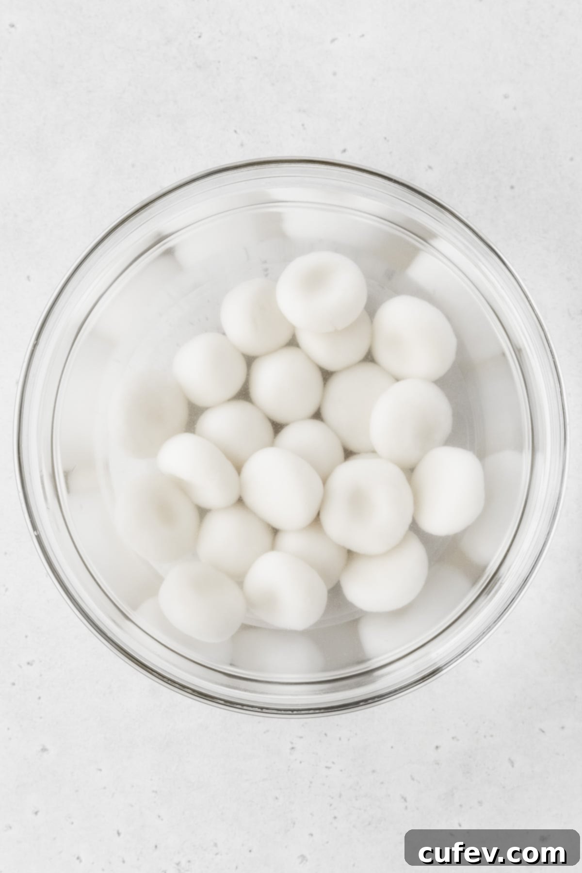 Boiled shiratama cooling in a glass bowl of cold water.