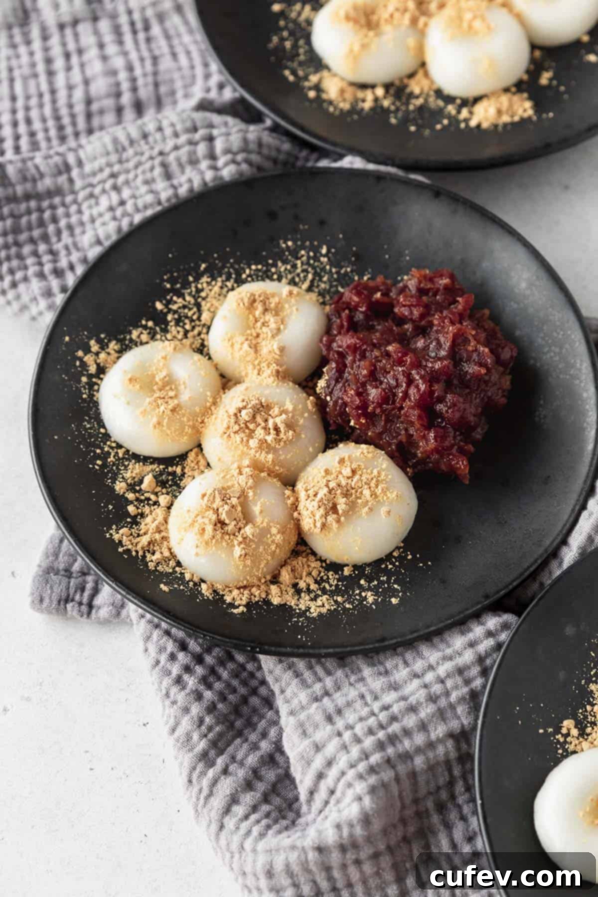 5 shiratama dango on a black plate with kinako and anko paste.