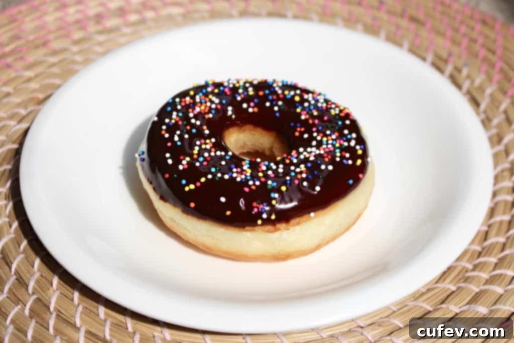 Golden brown, fluffy homemade yeasted doughnuts ready for glazing or toppings, with a bread machine in the background. Perfect for breakfast or dessert!