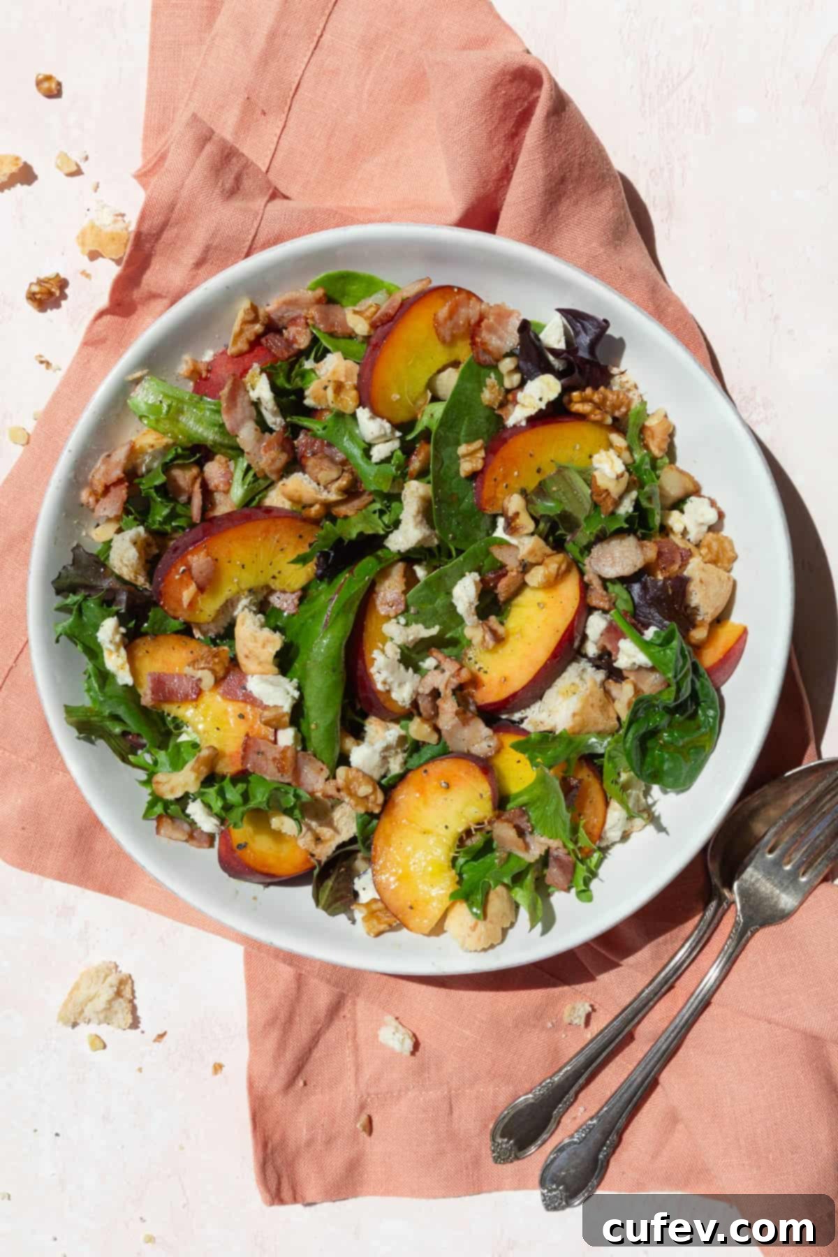 Peach salad with cheese and bacon in a white bowl on a pink linen.