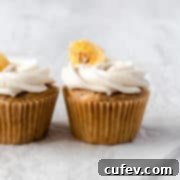 Vegan banana cupcakes topped with vegan buttercream, looking perfectly frosted and delicious on a white surface.