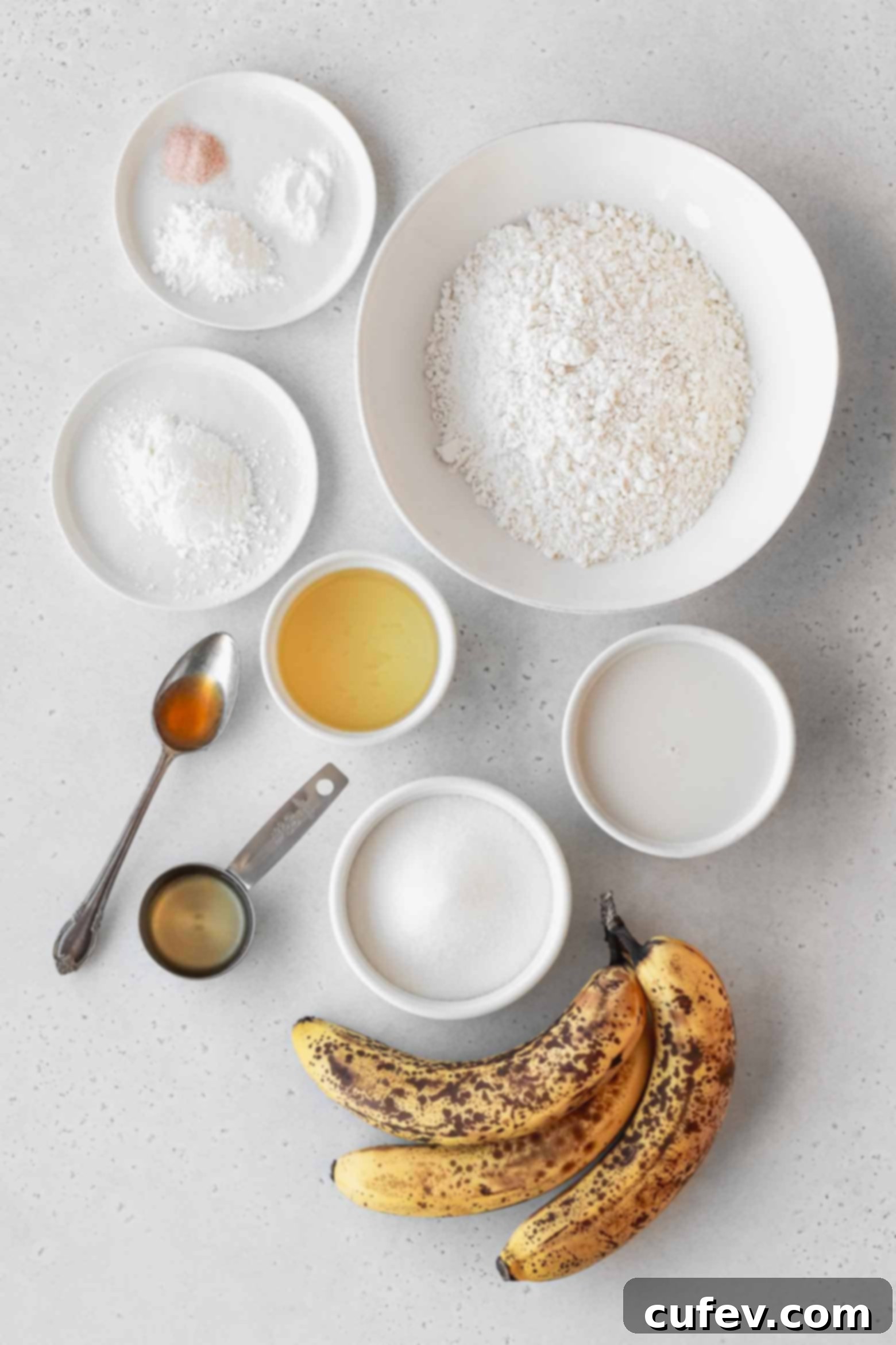 Ingredients to make homemade banana cupcakes measured out into bowls, including flour, sugar, mashed bananas, and liquids.