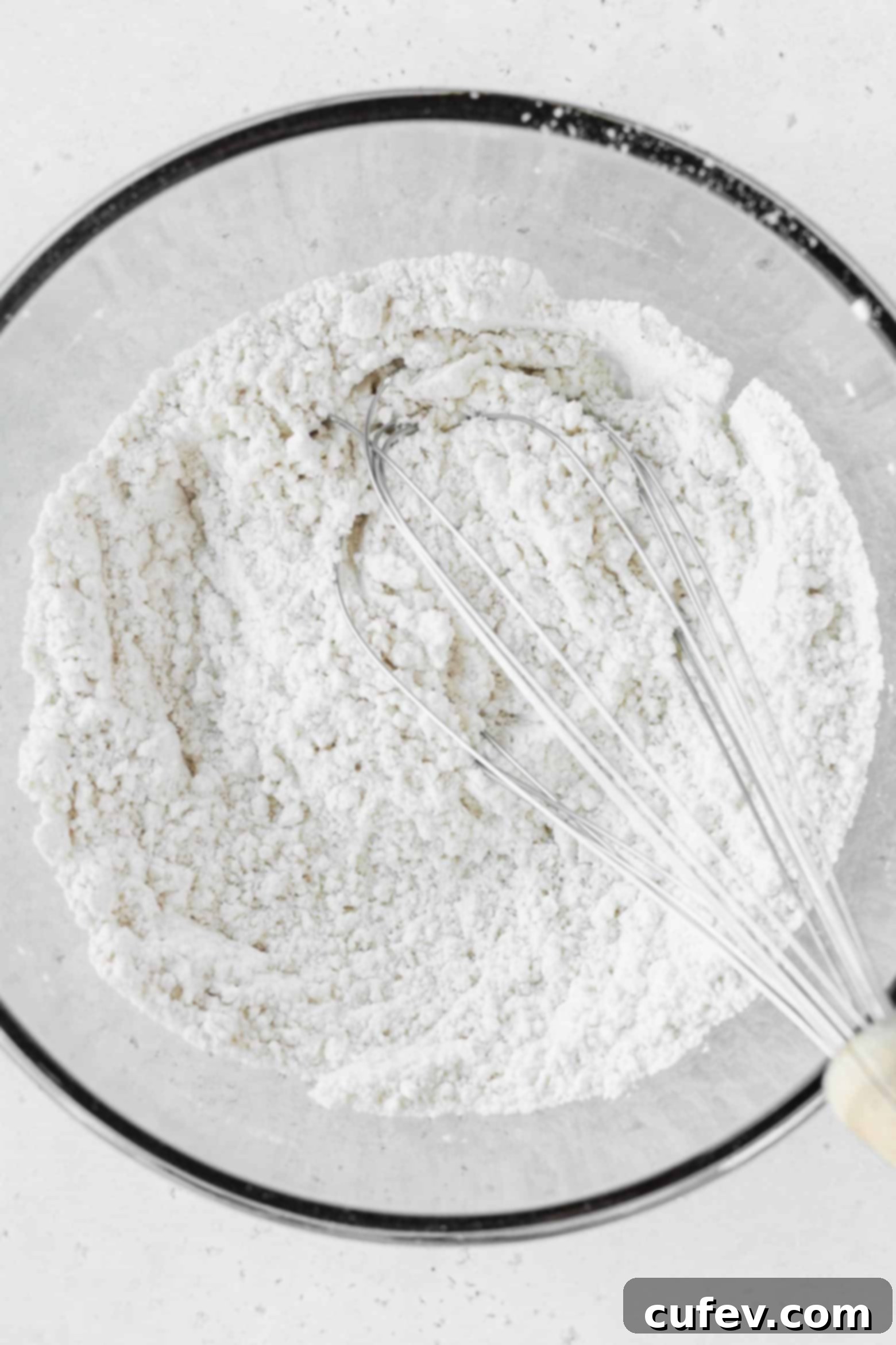 A bowl of cake flour and a whisk, representing the dry ingredients.