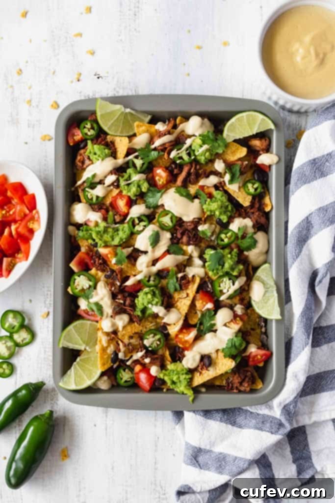 A close-up of fully loaded vegan jackfruit nachos, ready to be served, highlighting all the fresh and colorful toppings.