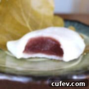 A square shot of kashiwa mochi with red bean filling with a bite taken out.