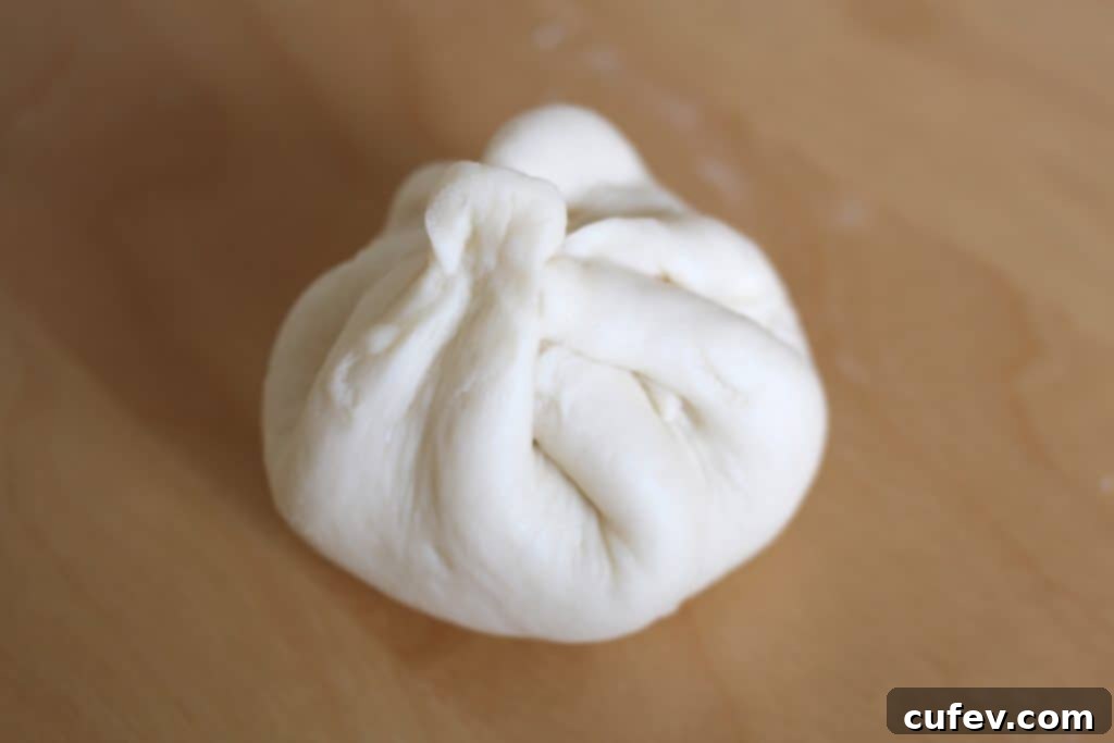 A beautifully shaped steamed pork bun, demonstrating the simple yet effective pinching technique.