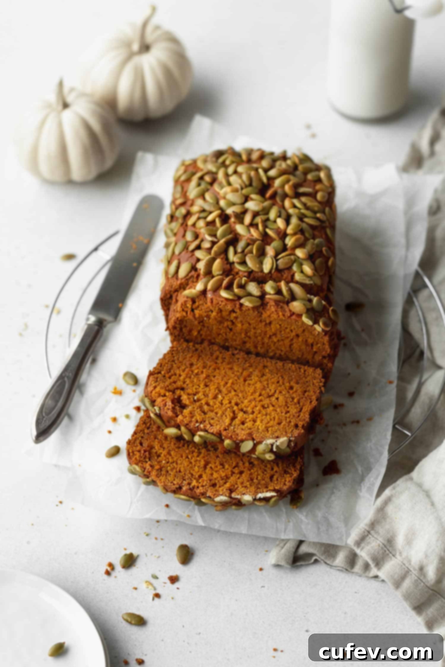 A sliced loaf of super moist gluten-free pumpkin bread, garnished with pepitas.