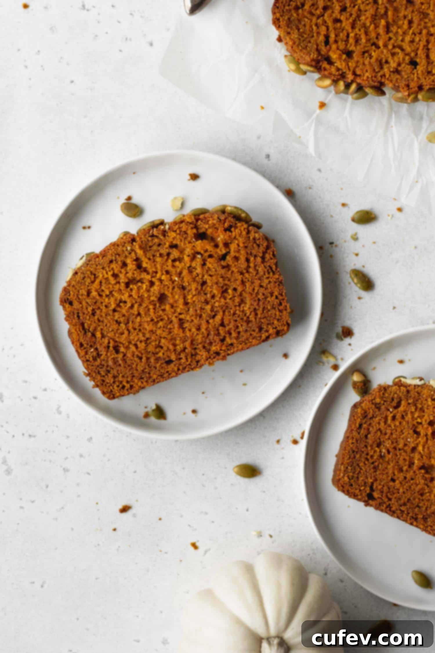 A perfectly sliced piece of moist gluten-free pumpkin bread on a white plate, showcasing its tender crumb.